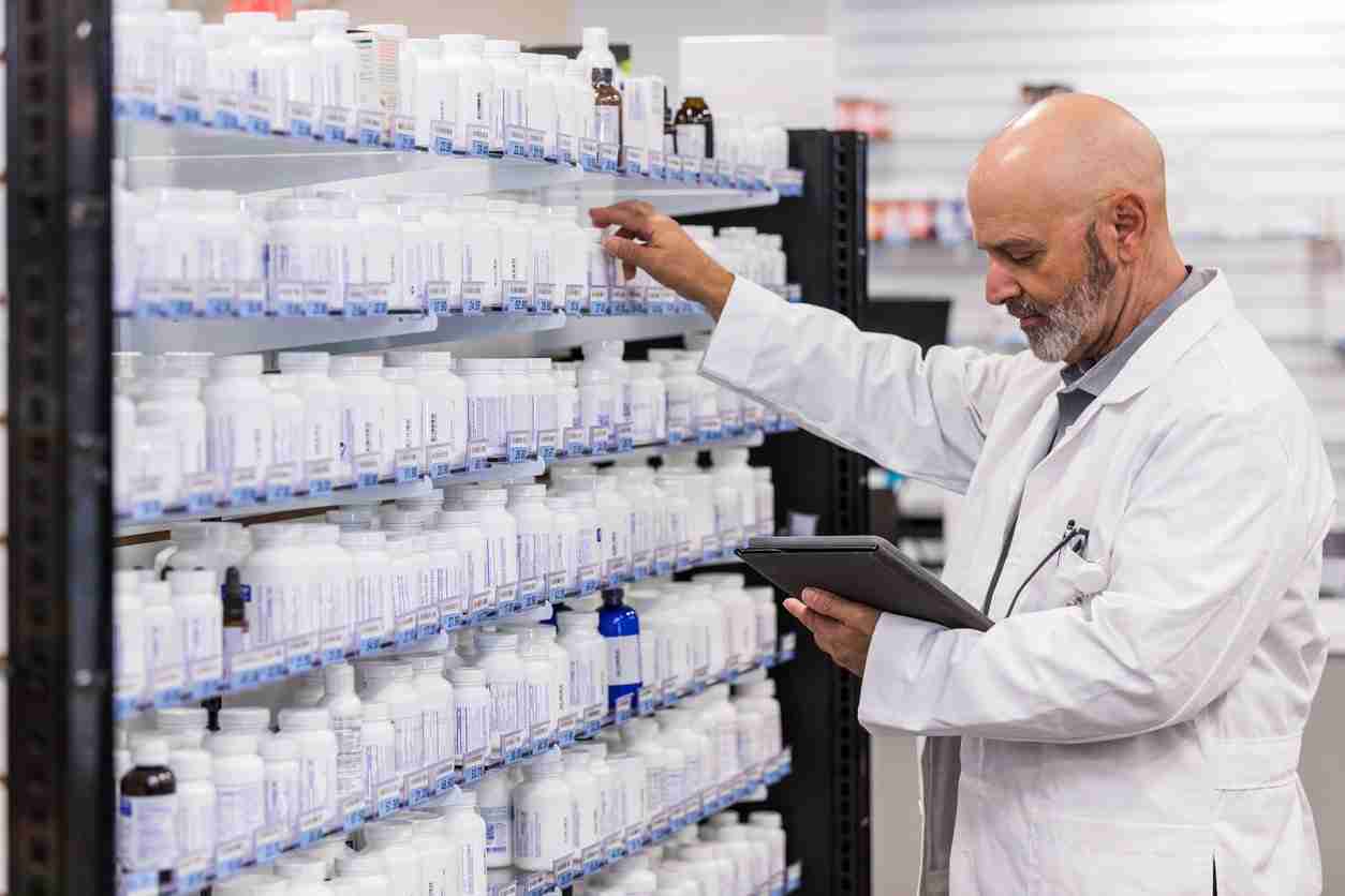 Mature pharmacist checks inventory